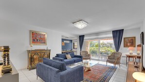 Ein modernes Wohnzimmer mit einem blauen Sofagarnitur, einer Kristallleuchtre und einem großen Fenster mit Vorhängen.