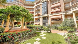 Ein mehrgeschossiges Hotel mit Innenhof, der einen Rosengarten mit roten Rosen und einen Pflasterweg beherbergt.