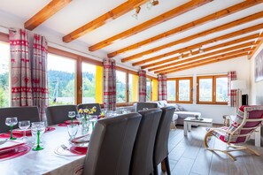 Un comedor con vigas de madera, ventanas amplias y vistas al exterior.