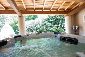 A hot tub area with wooden beams, clear water, and a view of lush greenery. - Chante Quinson - Charmant apt avec piscine (Les Assions)