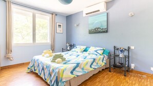 Een slaapkamer met een bed, nachtkastje, wandplank en raam.