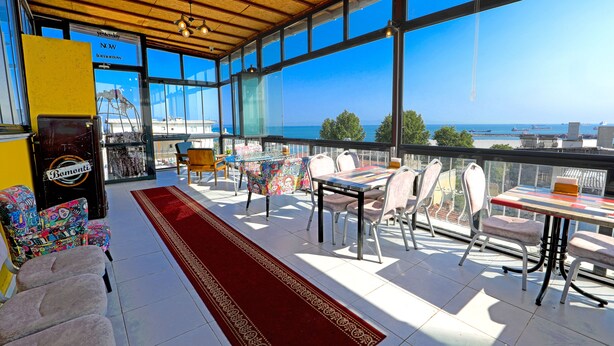 A spacious balcony with a red carpet, a table with chairs, and a view of the sea and ships. - Kondoskali Hotel (Istanbul)
