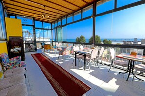 A spacious balcony with a red carpet, a table with chairs, and a view of the sea and ships. - Kondoskali Hotel (Istanbul)