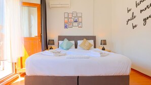 A neatly made bed with pillows, a bedside table with a lamp, and a wall with framed pictures and a motivational quote. - Kondoskali Hotel (Istanbul)