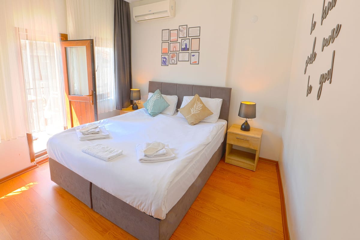 A neatly made bed with pillows, a bedside table with a lamp, and a wall with framed pictures.