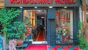 The entrance of Kondoskali Hotel with a red carpet, potted plants, and a glass door leading inside. - Kondoskali Hotel (Istanbul)