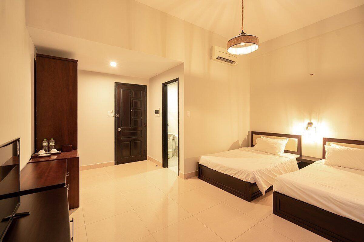 A hotel room with two beds, a desk, and a door leading to a bathroom.
