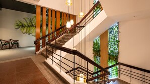 A modern staircase with wooden railings and hanging lights, surrounded by greenery and a large plant. - Danapearl Riverside Condotel (Da Nang)