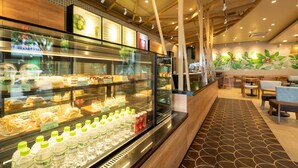 A bakery display case with pastries and a refrigerated section with bottled water and soda. - Danapearl Riverside Condotel (Da Nang)