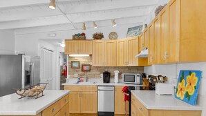 Una cocina moderna con gabinetes de madera, electrodomésticos de acero inoxidable y una isla central.