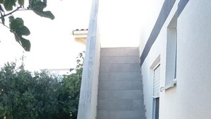 A staircase leading to a building with a stone floor and a car parked nearby. - App. 80 meters from the sea (Vir)