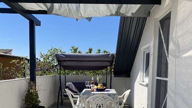A covered patio area with a table and chairs, a potted plant, and a grill. - App. 80 meters from the sea (Vir)