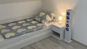 A small, modern bedroom with a single bed, a nightstand, a lamp, and a tall speaker unit. - App. 80 meters from the sea (Vir)