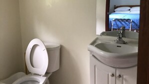 A bathroom with a toilet, sink, and a shelf with towels. - Coach House Motel 20 km East Terrace Bay (Unorganized Thunder Bay District)