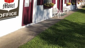 A motel with a red and white exterior, a sign reading "The Coach House Motel Office", and outdoor seating with potted plants. - Coach House Motel 20 km East Terrace Bay (Unorganized Thunder Bay District)