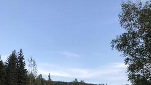 A row of cabins with a gravel driveway leading to a parking area, surrounded by trees and a clear sky. - Coach House Motel 20 km East Terrace Bay (Unorganized Thunder Bay District)