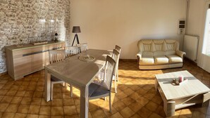 A dining area with a wooden table and chairs, a sofa, and a small table with a candle.