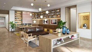 Een moderne woonkamer met een bruine leren bank, een houten salontafel en boekenkasten vol boeken.