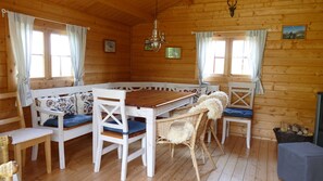 A wooden cabin with a large dining table, white chairs, and a cozy seating area. - Vacation apartment Eifelbergblick with garden, Schleiden, Hiking Eifel National Park (Schleiden)