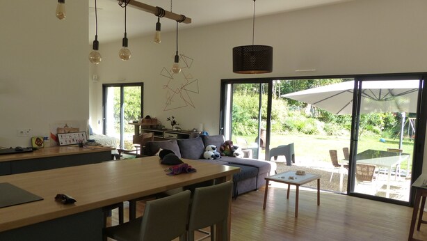 A modern kitchen with a central island, dining area with chairs, and a large sliding glass door leading to a patio.