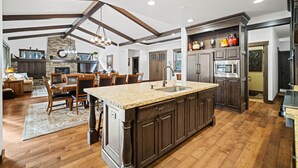 A spacious kitchen with a large island, wooden beams, and built-in appliances.