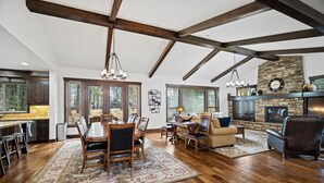 A spacious living area with a wooden dining table, comfortable seating, and a fireplace.