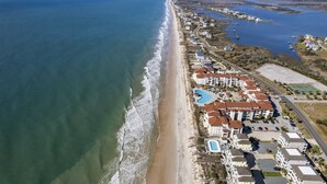 Luftaufnahme eines Küstenresorts mit Strandvillen, einem Swimmingpool und einer Marina.