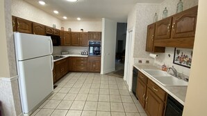 Une cuisine avec des meubles de rangement en bois, un réfrigérateur blanc, une cuisinière et un évier.