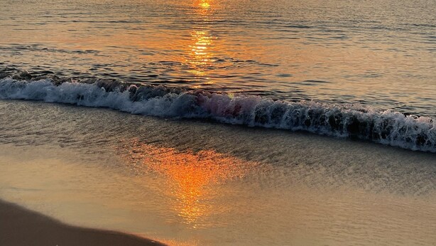 Una playa con un atardecer sobre el océano.