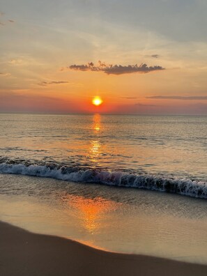 Una playa con un atardecer sobre el océano.