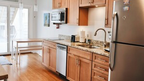 Una cocina moderna con armarios de madera, electrodomésticos de acero inoxidable, encimera de granito y lavavajillas.