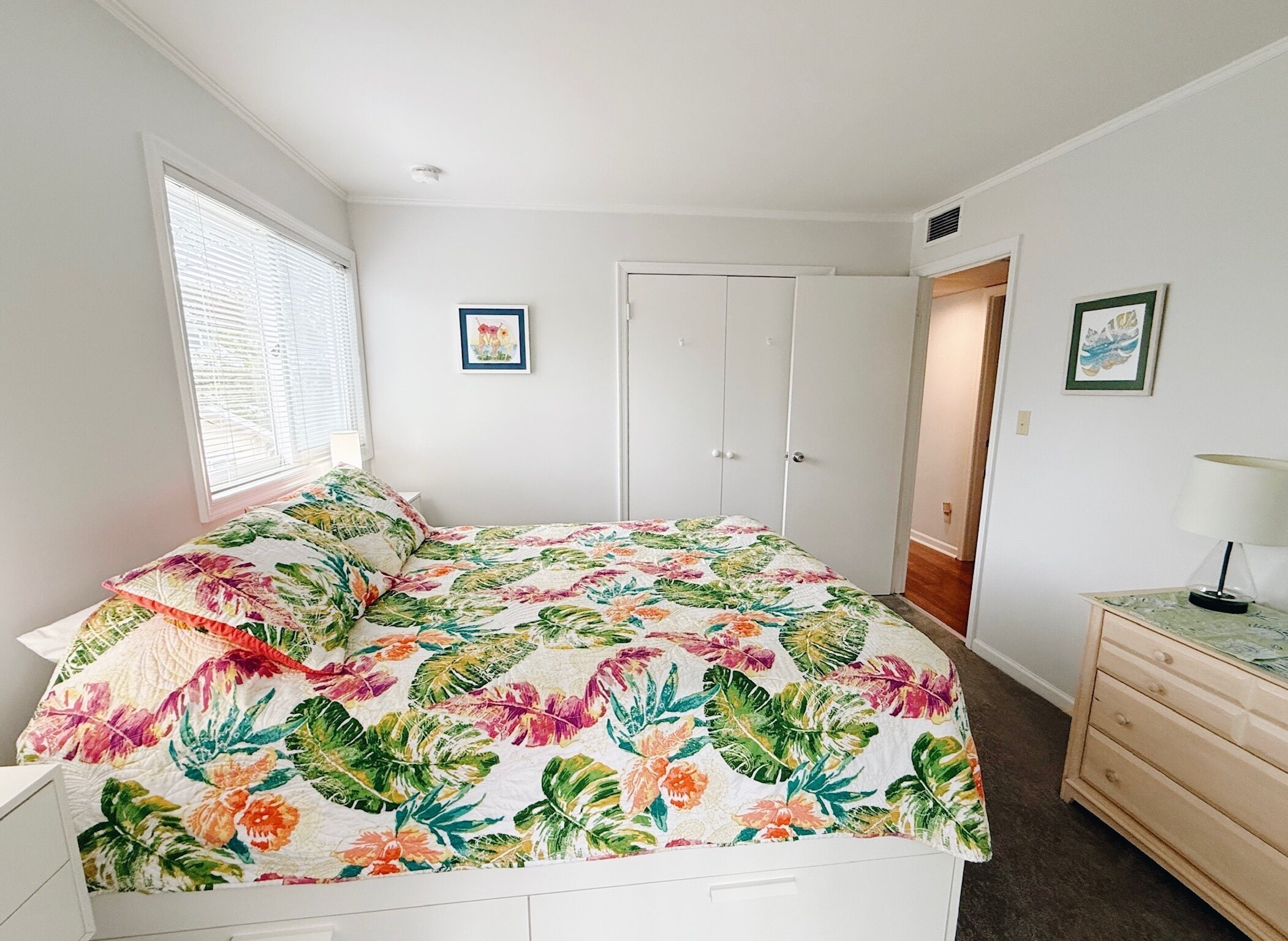 Une chambre à coucher avec un lit, une table de chevet, une commode et une porte.