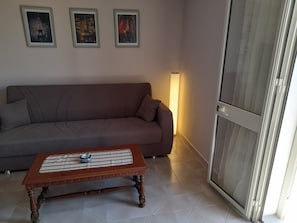 Una sala de estar con un sofá marrón, una mesa de centro de madera y tres cuadros en la pared.