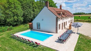 Ein Haus mit Swimmingpool, Sitzgelegenheiten im Freien und einem Garten.