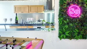 Eine moderne Küche mit Holzausstattung, einer Edelstahl-Dunstabzugshaube und einer Neonreklame an einer grünen Wand.