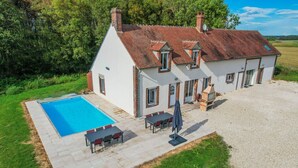Ein Haus mit Schwimmbad, Sitzgelegenheiten im Freien und Grillplatz.