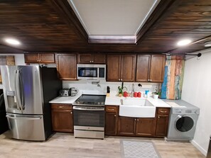Une cuisine moderne avec des meubles en bois, des appareils en acier inoxydable et un four à micro-ondes encastré.