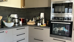A modern kitchen with a built-in oven, a coffee maker, and a small wooden stool. - Rental House Quiberon 6 beds (Quiberon)