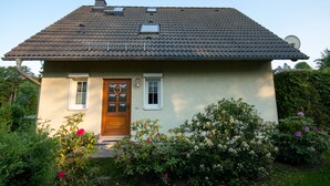 A two-story house with a tiled roof, a front door with a wreath, and a satellite dish.