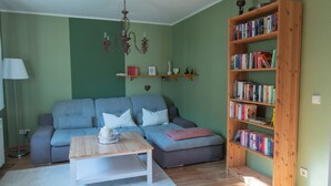 A living room with a sofa, a coffee table, a bookshelf, and a chandelier.