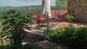 Un patio con una mesa y sillas, un edificio de piedra y vistas al campo.