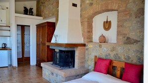 Una habitación acogedora con chimenea de piedra, una cama con almohadones rojos y un aparador de madera.