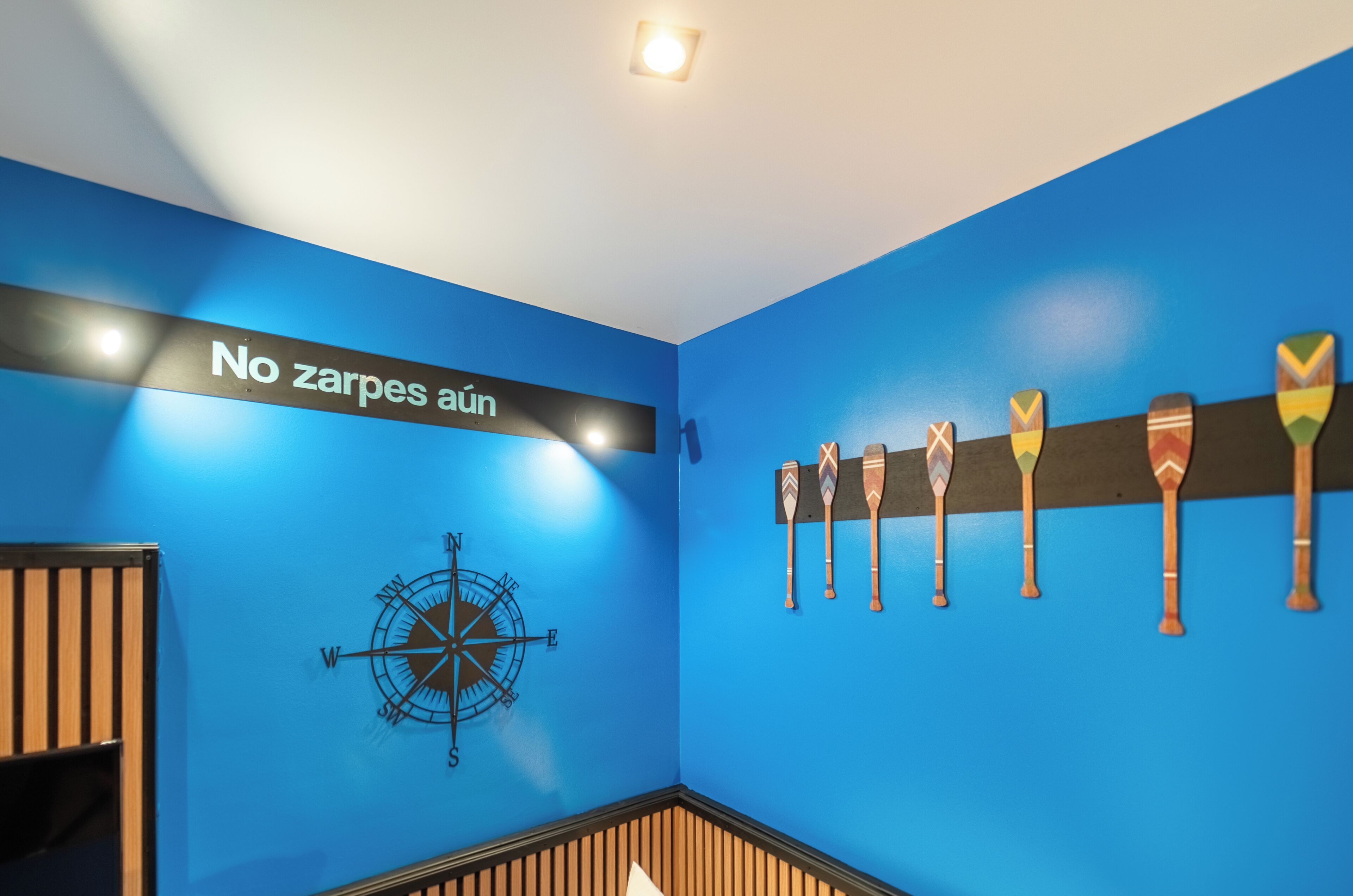 A room with blue walls, a compass, and a sign that says 'No zarpes aun.'