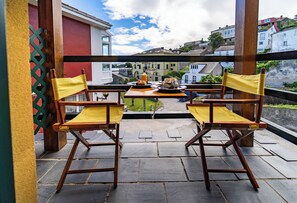 A balcony with two wooden chairs and a table with a bottle and a glass. - Hotel A. G. Porcillán (Ribadeo)