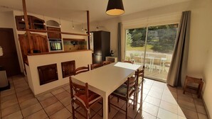 Una cocina amplia con comedor, armarios de madera y un ventanal con vistas al exterior.