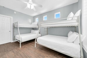 A room with two bunk beds, a door, a ceiling fan, and a window. - Timeless Traditions-Golf Cart Deals-Steps to Beach (Destin)