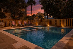 A swimming pool with lounge chairs and a wooden fence. - Timeless Traditions-Golf Cart Deals-Steps to Beach (Destin)