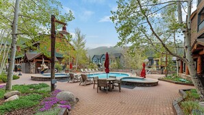 A pool area with lounge chairs, a table, and red umbrellas. - Townhome w/ Private Saltwater Hot Tub Near Keystone Ski Village (Keystone)