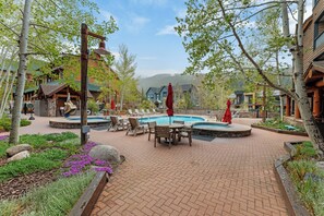 A pool area with lounge chairs, a table, and red umbrellas.