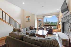 A living room with a sofa set, a coffee table, a fireplace, and a TV.
